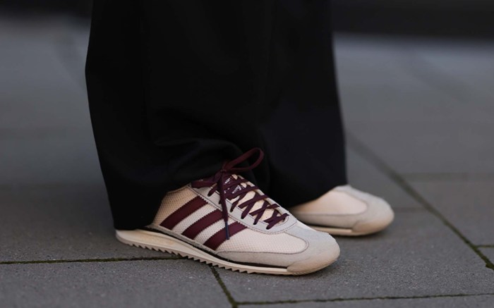 person wears beige and burgundy Adidas shoes with black pants