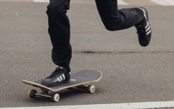 Person skateboarding in black adidas skate shoes