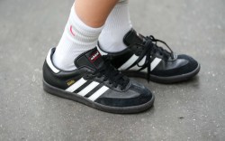 Woman wears white socks, black leather and suede Samba sneakers from Adidas, during a street style fashion photo