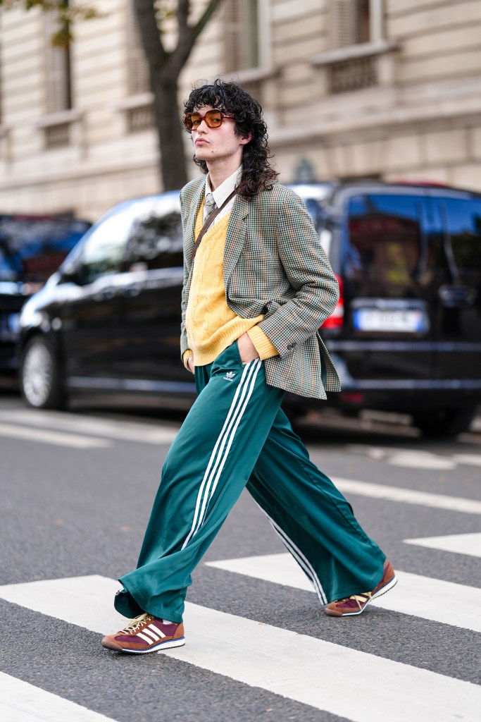 PARIS, FRANCE - OCTOBER 01: Loic Hornekcer wears dark brown sunglasses, white buttoned up long sleeve shirt, light yellow knit sweater light green tie, light green pattern blazer jacket, dark green Adidas Originals white striped pants, dark brown suede Adidas Originals Gazelle sneaker shoes, outside Miu Miu, during the Paris Fashion Week Spring/Summer 2025 on October 1, 2024 in Paris, France (Photo by Edward Berthelot/Getty Images)